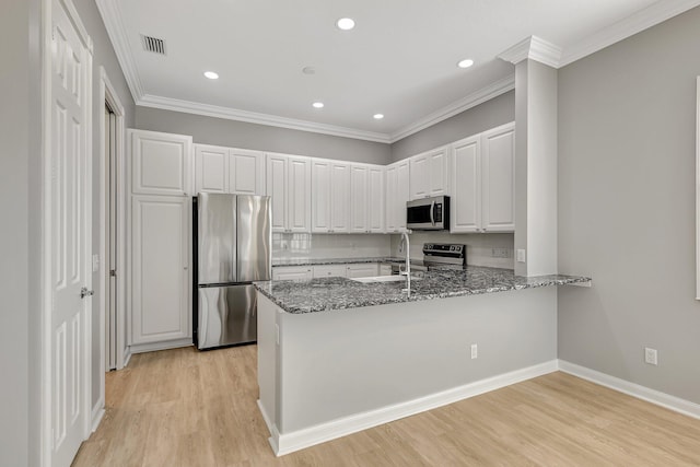 kitchen featuring light hardwood / wood-style floors, dark stone counters, white cabinets, kitchen peninsula, and appliances with stainless steel finishes