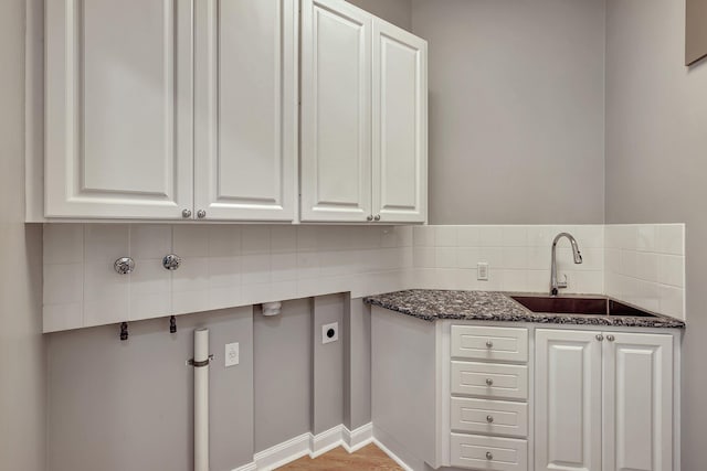 kitchen featuring white cabinetry, sink, dark stone countertops, and backsplash