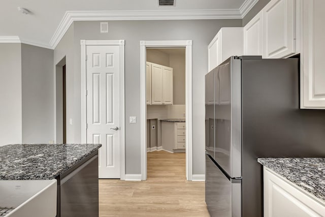 kitchen featuring stainless steel fridge, white cabinetry, light wood-type flooring, and dark stone countertops