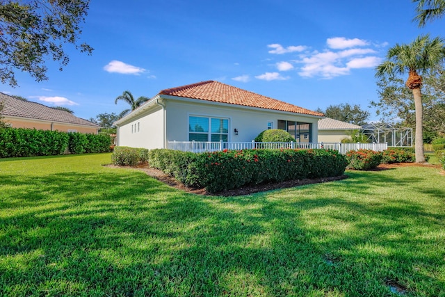 back of property with glass enclosure and a lawn