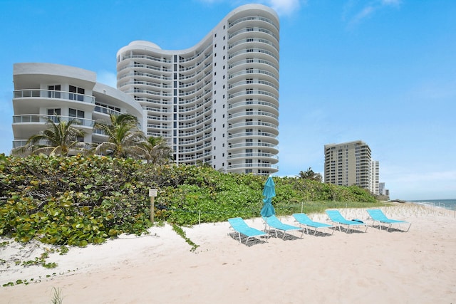 view of building exterior featuring a water view and a beach view