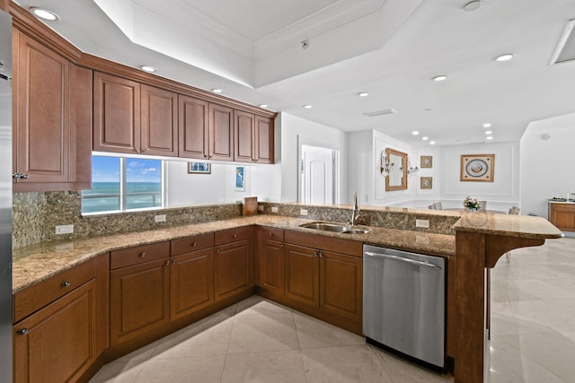 kitchen featuring kitchen peninsula, light stone counters, stainless steel dishwasher, ornamental molding, and sink