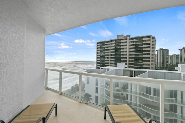 balcony featuring a water view and a beach view