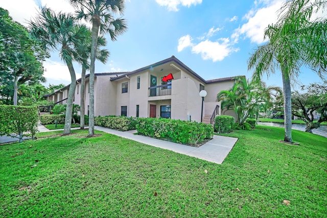 view of front of property featuring a balcony and a front yard