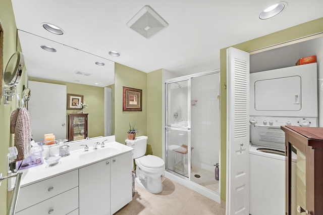 bathroom featuring tile patterned flooring, stacked washer / dryer, toilet, vanity, and a shower with shower door