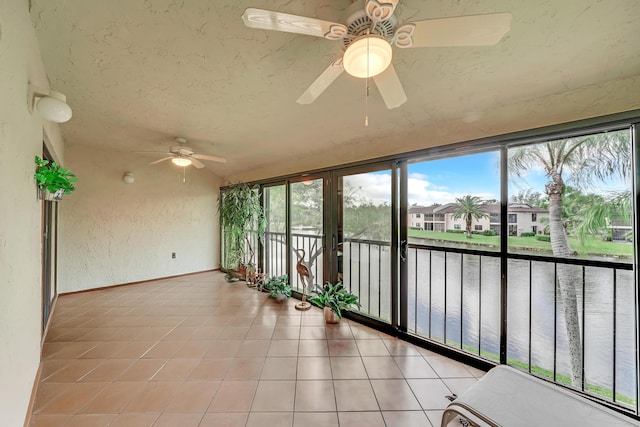 unfurnished sunroom with ceiling fan, french doors, and a water view