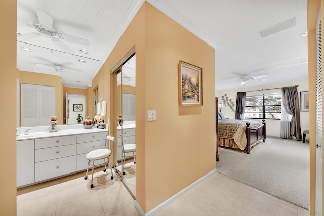 corridor featuring a textured ceiling, light colored carpet, crown molding, and sink