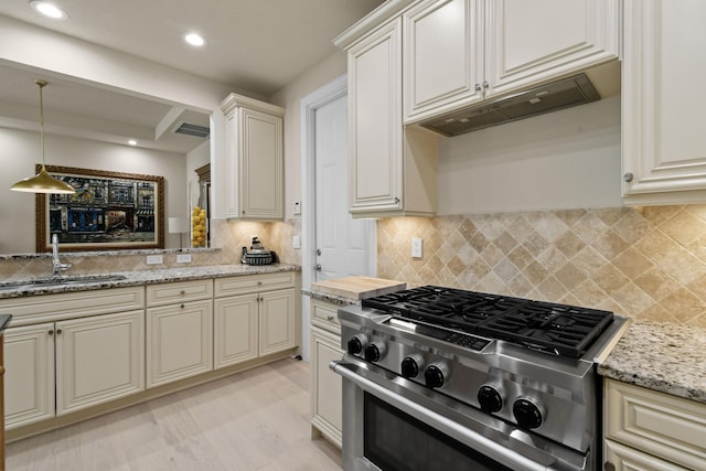 kitchen featuring pendant lighting, sink, high end range, decorative backsplash, and light stone counters