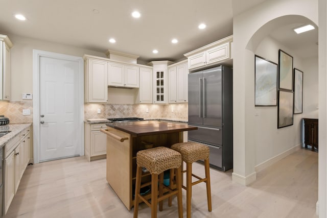 kitchen with tasteful backsplash, high quality fridge, a center island, and dark stone counters