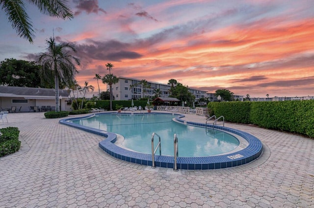 pool at dusk with a patio area