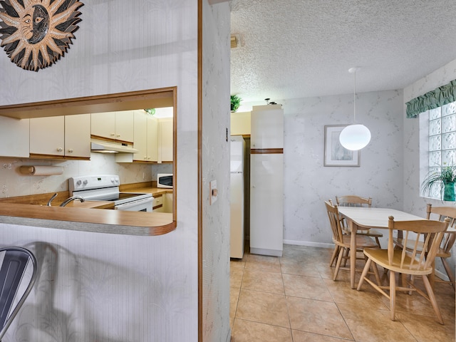 kitchen featuring pendant lighting, a textured ceiling, light tile patterned flooring, and white appliances