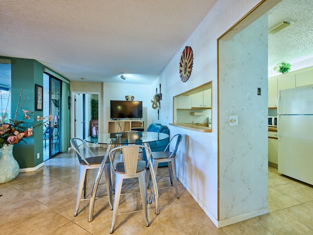 tiled dining space with a textured ceiling