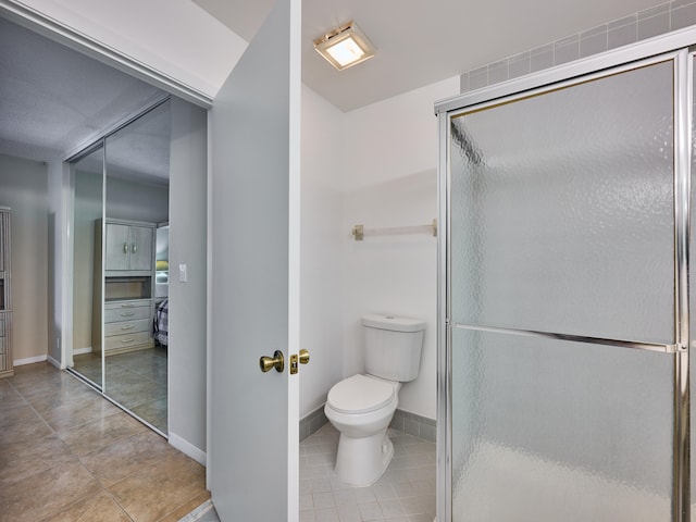 bathroom featuring vanity, a shower with door, tile patterned flooring, and toilet