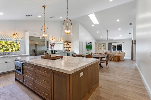 kitchen featuring built in appliances, hanging light fixtures, white cabinets, light hardwood / wood-style floors, and a skylight