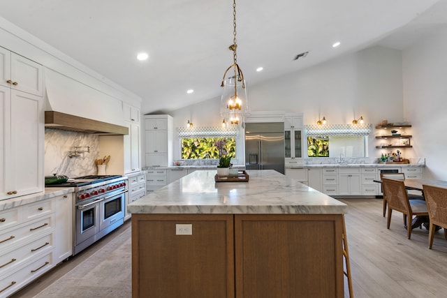 kitchen featuring high quality appliances, lofted ceiling, a kitchen island, and white cabinets