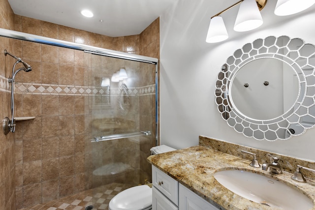 bathroom featuring toilet, a shower with shower door, and vanity