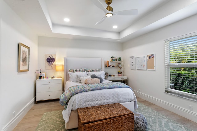 bedroom with a raised ceiling, light hardwood / wood-style floors, and ceiling fan