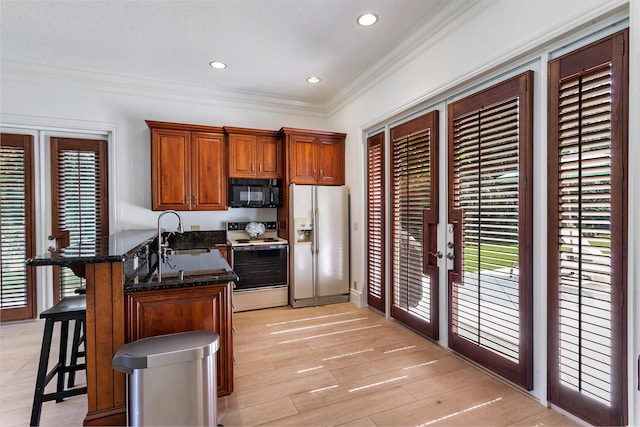 kitchen with a breakfast bar area, white electric range, kitchen peninsula, sink, and refrigerator with ice dispenser