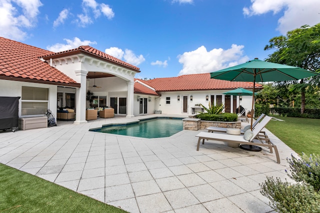 view of pool featuring outdoor lounge area, a patio area, a lawn, and ceiling fan