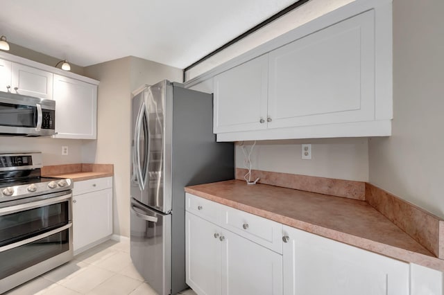 kitchen featuring white cabinetry, stainless steel appliances, and light tile patterned floors