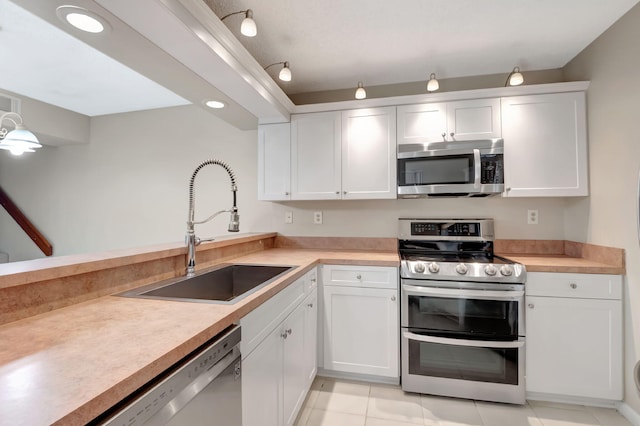 kitchen with light tile patterned floors, appliances with stainless steel finishes, sink, and white cabinets