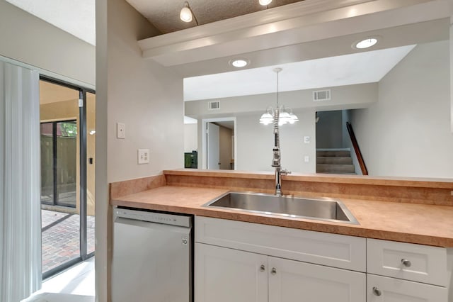 kitchen featuring dishwasher, sink, pendant lighting, an inviting chandelier, and white cabinets