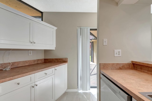 kitchen featuring white cabinetry, dishwasher, light tile patterned flooring, and a textured ceiling