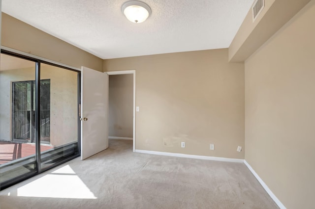 unfurnished room featuring a textured ceiling and light colored carpet