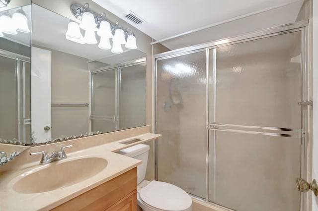 bathroom featuring toilet, vanity, and a shower with door