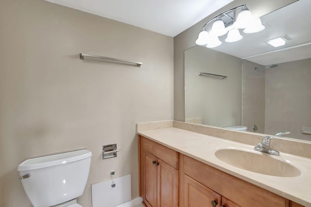 bathroom with vanity, a tile shower, and toilet