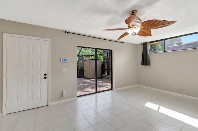 empty room featuring a textured ceiling, light tile patterned floors, and ceiling fan