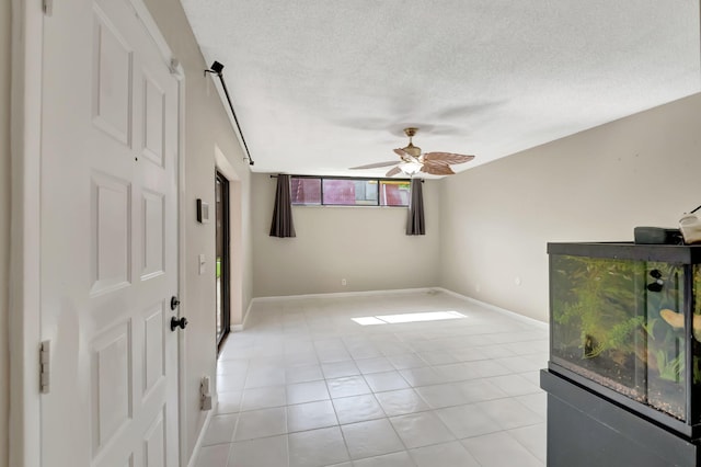 unfurnished room with ceiling fan, a textured ceiling, and light tile patterned floors