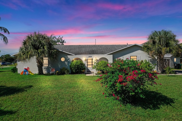 ranch-style home featuring stucco siding and a lawn