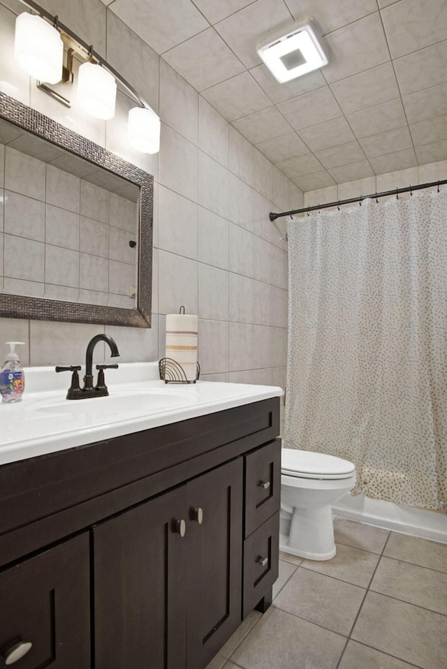 bathroom with tile walls, toilet, vanity, curtained shower, and tile patterned floors