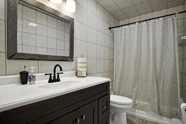 bathroom with tile walls, toilet, shower / tub combo with curtain, tile patterned flooring, and vanity