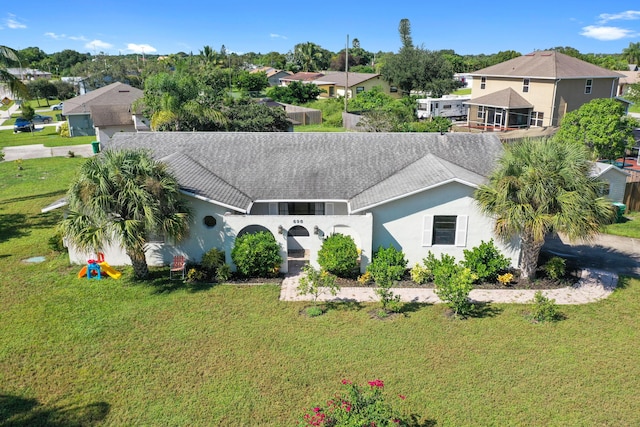 ranch-style house with roof with shingles, stucco siding, a residential view, and a front lawn