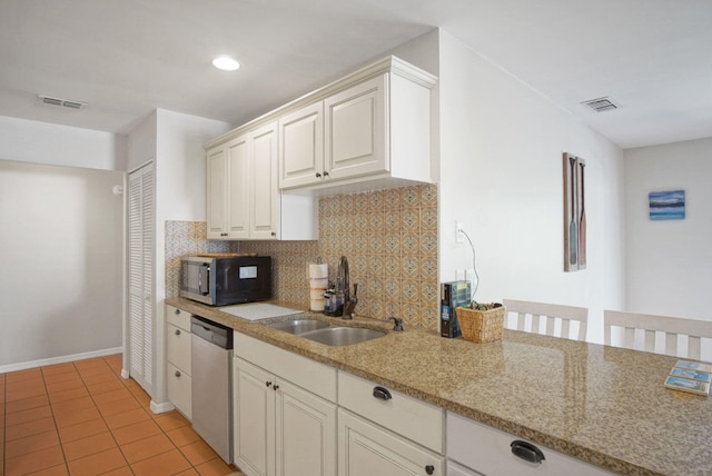 kitchen featuring light stone counters, backsplash, appliances with stainless steel finishes, light tile patterned flooring, and sink