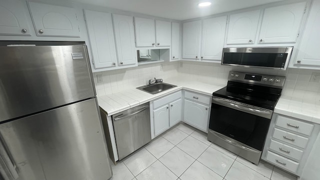 kitchen featuring white cabinetry, appliances with stainless steel finishes, decorative backsplash, and tile counters