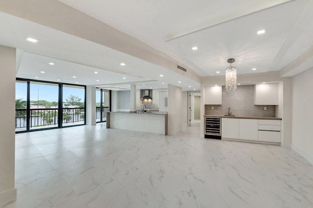 kitchen featuring wine cooler, tasteful backsplash, pendant lighting, and white cabinets