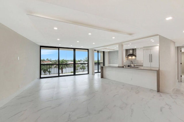 unfurnished living room with a wall of windows and sink