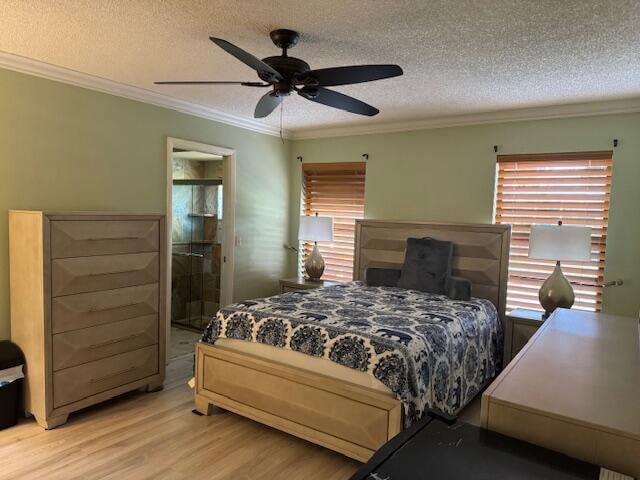 bedroom with ensuite bath, ceiling fan, crown molding, a textured ceiling, and light wood-type flooring