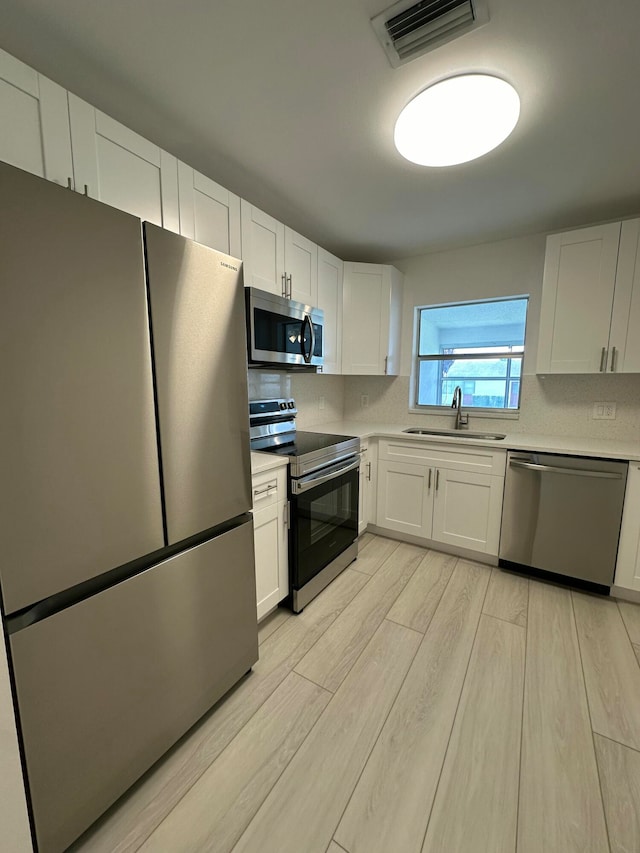 kitchen featuring light hardwood / wood-style floors, stainless steel appliances, sink, and white cabinets