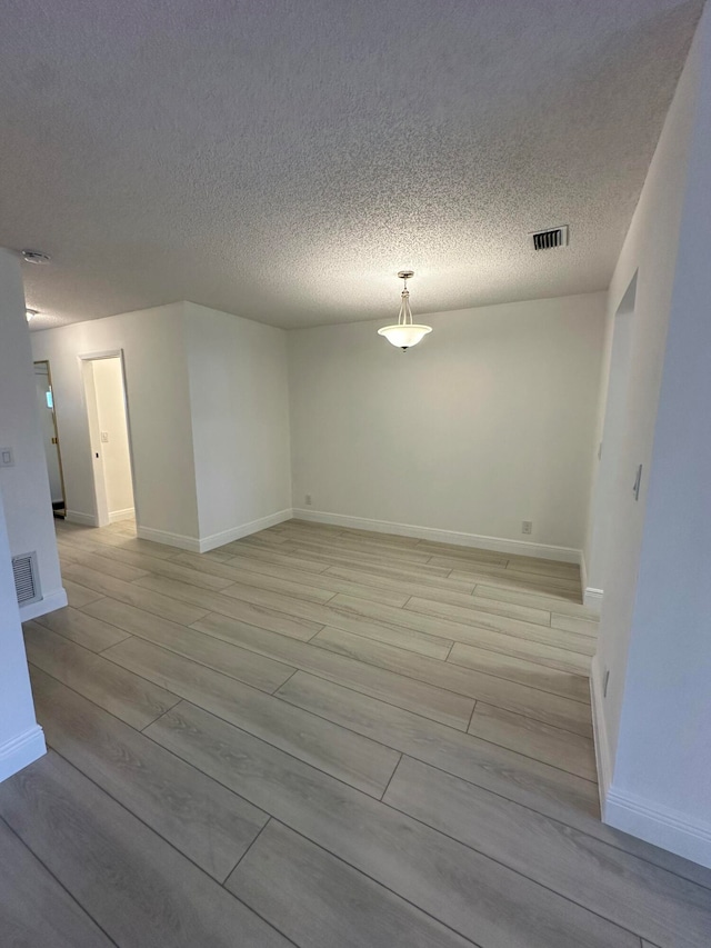 unfurnished room with light hardwood / wood-style floors and a textured ceiling