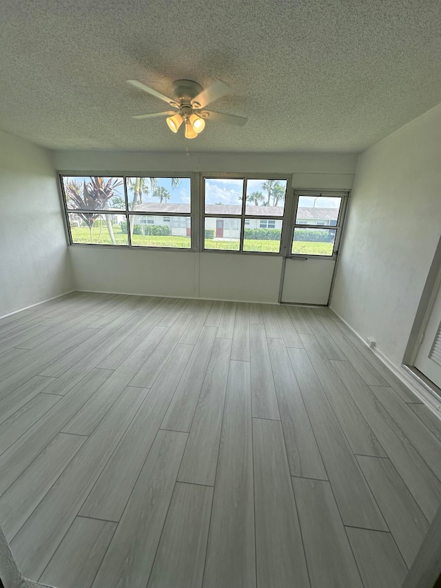 unfurnished sunroom with ceiling fan