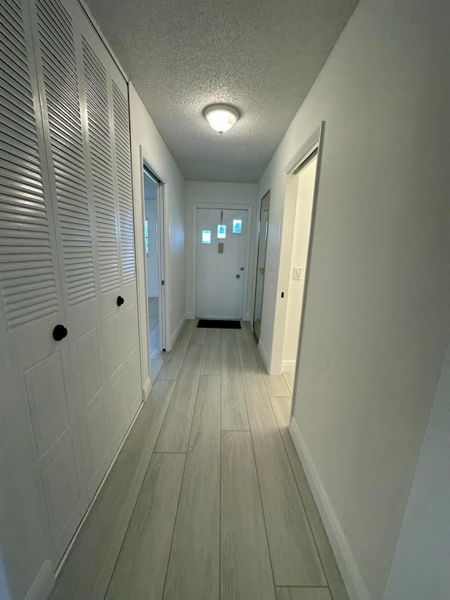 hallway featuring light hardwood / wood-style floors and a textured ceiling