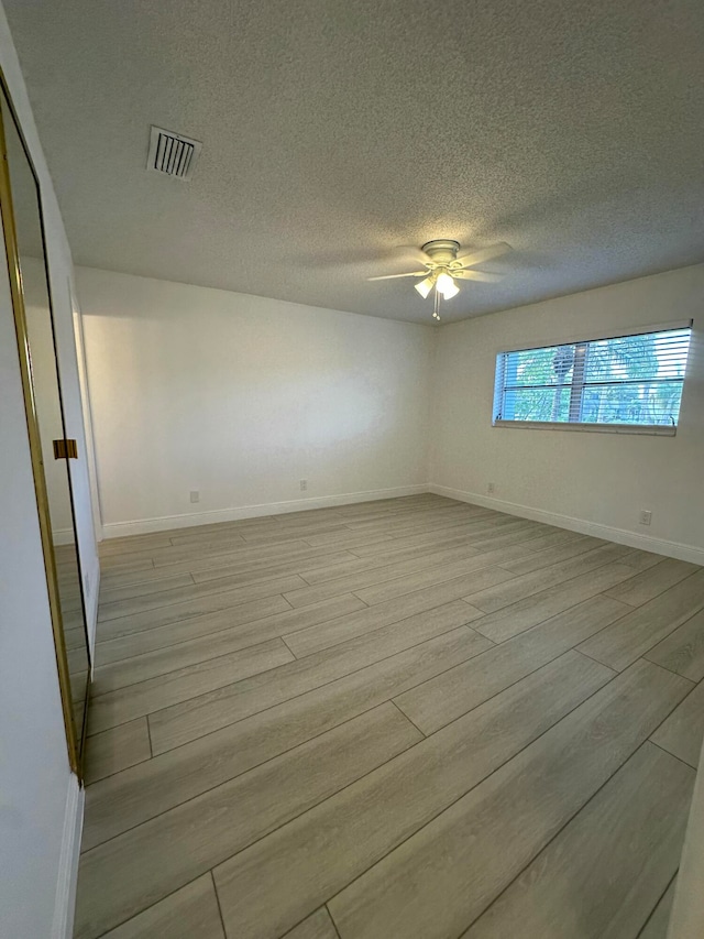 empty room featuring ceiling fan, a textured ceiling, and light hardwood / wood-style flooring