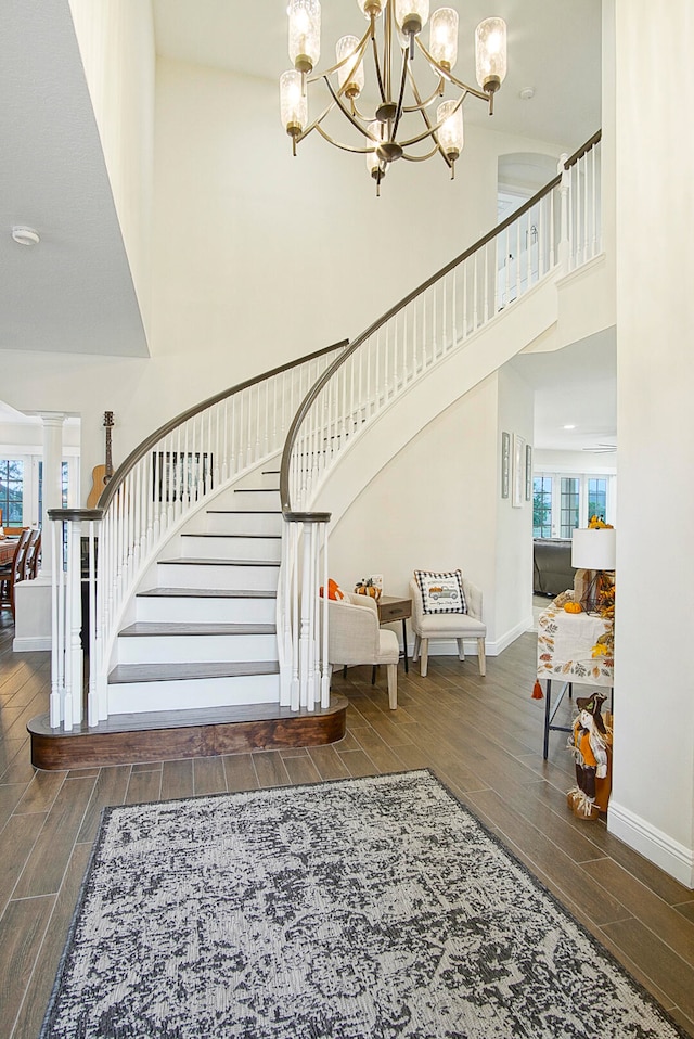 staircase with a towering ceiling, a wealth of natural light, and hardwood / wood-style floors