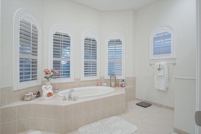 bathroom with tiled bath, a healthy amount of sunlight, and tile patterned floors