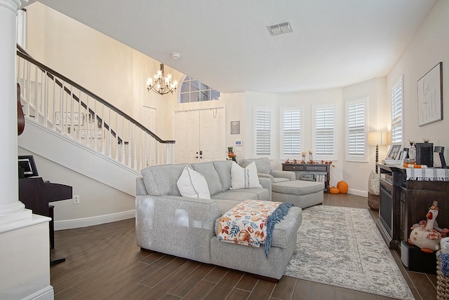 living room featuring a notable chandelier, ornate columns, and dark hardwood / wood-style floors