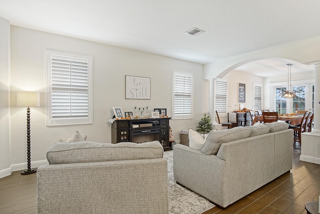 living room featuring a healthy amount of sunlight, hardwood / wood-style flooring, and decorative columns